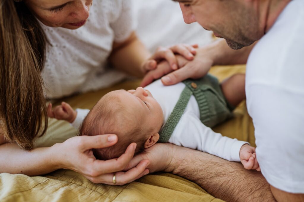 Happy parents cuddling with their newborn baby.